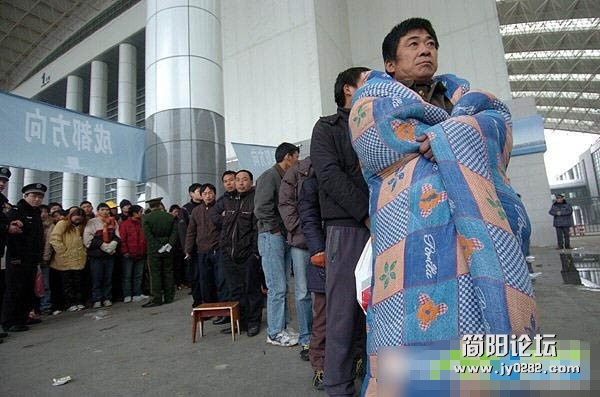 2009年1月2日，在宁波国际会展中心临时售票点，一名排了两天队的购票者披着棉被等待买.jpg