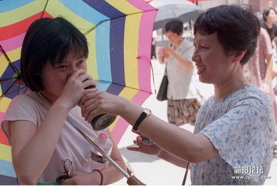 1997年有二百八十四万毕业生参加高考。图为母亲想女儿递上饮料。.jpg