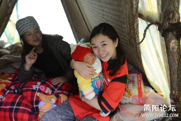 廖智看望一位在窝棚里坐月子的新妈妈时，抱着小宝宝爱不释手。.jpg